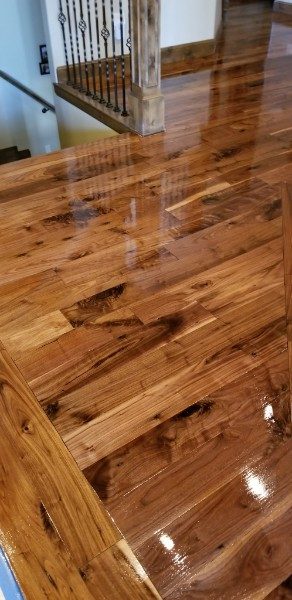 A high-gloss hickory floor reflecting a staircase and railing