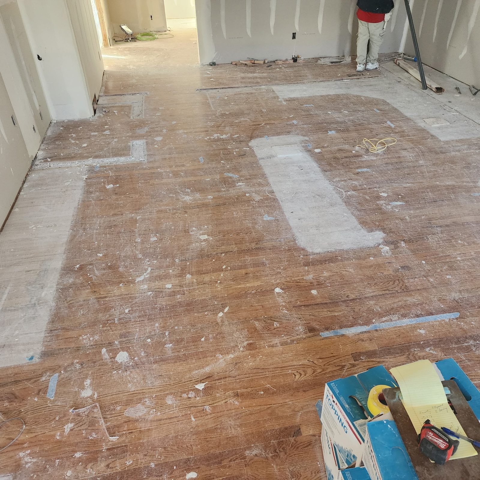 A stripped floor during remodel work with patched sections and prep compound